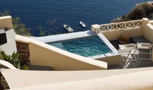 a swimming pool on top of a house next to the water at THE A COLLECTION by K&K in Oia