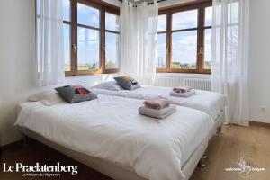 two beds in a room with large windows at Combo Praelatenberg 2 appartements dans la même maison in Orschwiller