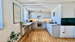 a kitchen with white cabinets and a wooden floor at The Quaker Hall - Private Deck - Stunning Views in Falmouth +34 photos
