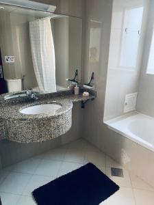 a bathroom with a sink and a mirror and a tub at Rest House Hostel in Abu Dhabi