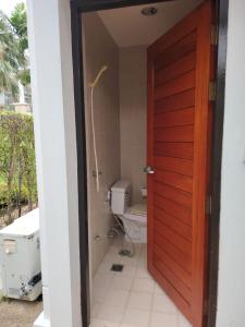 a bathroom with a toilet and a wooden door at Hua Hin Blue Lagoon Island Villa A Family Paradise in Ban Nong Chaeng +1 photo