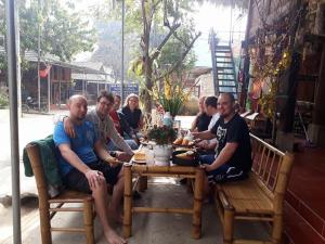 eine Gruppe von Menschen sitzt um einen Holztisch in der Unterkunft An' Home Mai Chau in Mai Châu