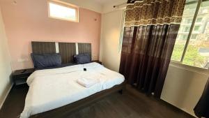 博瓦利Sk inn hotel的卧室里有一张铺着白色床单的床和一扇窗户