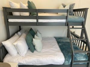 a bunk bed with white pillows on a bunk bed with a ladder at La Chaumiere - Charm and character in leafy green suburb in Caboolture