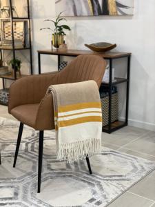 a brown chair with a blanket on the back at La Chaumiere - Charm and character in leafy green suburb in Caboolture +30 photos