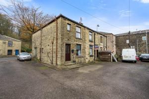 an old brick building with cars parked in a parking lot at 2 BR House By Eason Stays Short Lets & Serviced Accommodation Rossendale With Free Parking in Newchurch