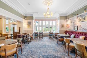 a restaurant with tables and chairs and a chandelier at Sidcot Arms in Winscombe
