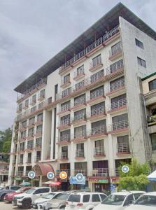 Un gran edificio con coches aparcados en un estacionamiento. en Baguio Transient Across Burnham Park 2 - 2BR Condo, en Baguio