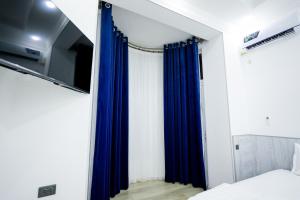 Schlafzimmer mit blauen Vorhängen und einem TV in der Unterkunft Chehran Hotel in Samarkand