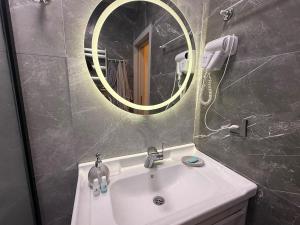 ein Badezimmer mit einem weißen Waschbecken und einem Spiegel in der Unterkunft Sea Breeze Park Residence 1 in Nardaran