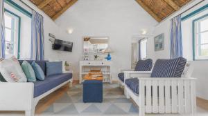 ein Wohnzimmer mit einem blauen Sofa und 2 Stühlen in der Unterkunft Zandtorini Seaside Cottage in Struisbaai