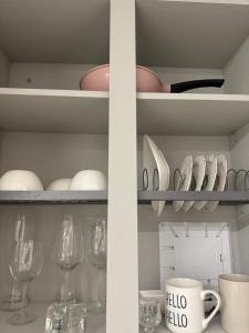 ein Regal mit Weingläsern, Tellern und einer Tasse in der Unterkunft Ocean GYM n Spa, free parking in Busan + 21 Fotos