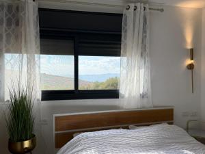 Un dormitorio con una cama y una ventana con vistas. en גרין פארק - קוטג' מהמם עם בריכה מחוממת וג'קוזי בעין קנייא, en Ein Kinya 9 fotos más