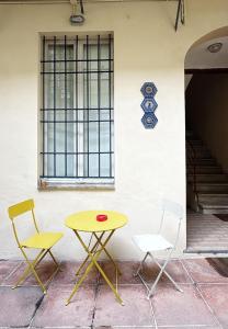 ein gelber Tisch und zwei Stühle vor einer Wand in der Unterkunft Faenza Apartments by Console Camprini Estates srl in Faenza