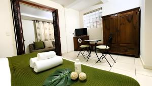 a bedroom with a green bed with a chair and a table at Hotel B&B - 5th Avenue in Playa del Carmen