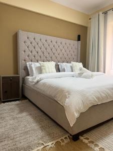 a large bed with a large headboard in a bedroom at Enzi Apartment Block A in Nairobi
