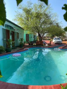 une piscine en face d'une maison avec un arbre dans l'établissement Bush Adventure Guest House, à Kasane