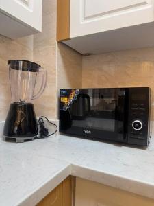a black microwave sitting on a counter in a kitchen at Enzi Apartment Block A in Nairobi +15 photos
