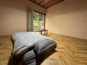 ein Schlafzimmer mit einem Bett und einem großen Fenster in der Unterkunft 一棟貸し Cottage CASA 屋久島空港近く利便性良し 森に囲まれ静かな一軒家 in Yakushima