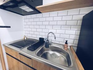 东京Plan A Tennozu Isle的厨房里设有不锈钢水槽,铺有白色瓷砖 更多40张照片