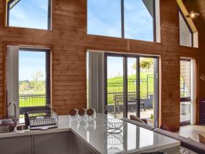 eine Küche mit großen Fenstern und einer Theke mit einem Tisch in der Unterkunft Centilen Pedr - Daffodil - Ukc7078 in Mydroilin