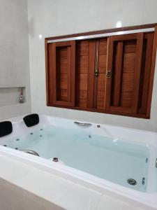 a white bath tub in a bathroom with wooden cabinets at Casa Limoeiro in Pirenópolis