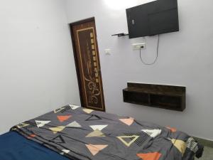 Un dormitorio con una cama y un televisor de pantalla plana. en Hotel vishram, en Aligarh