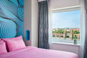 a bedroom with a pink bed and a window at nhow Berlin in Berlin
