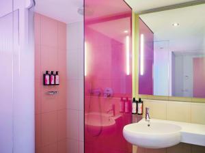 a pink bathroom with a sink and a shower at nhow Berlin in Berlin