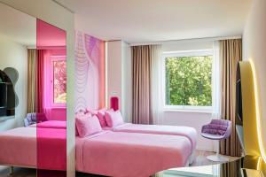 a pink bedroom with two beds and a window at nhow Berlin in Berlin +65 photos