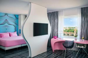a bedroom with a pink bed and a tv at nhow Berlin in Berlin
