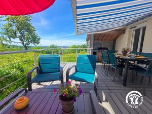 a deck with blue chairs and a table with a view at La Maison d'à côté in Taussac +8 photos