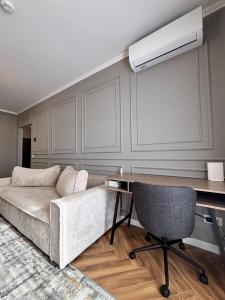 un salon avec un canapé et un bureau dans l'établissement Skyresort- Kingsize Bed, Close To The Airport, à Someşeni