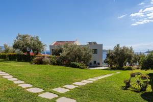a garden with a stone path and a house at Cape Blue Suites in Achladies