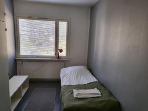 um pequeno quarto com uma cama e uma janela em Kotimaailma - kolmio Kotkasta em Kotka