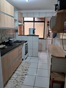 Il comprend une cuisine avec des placards en bois et du carrelage blanc. dans l'établissement Apartamento no centro de Capão da Canoa, à Capão da Canoa