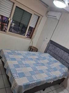 - une chambre avec un lit et une couverture en damier dans l'établissement Apartamento no centro de Capão da Canoa, à Capão da Canoa 22 autres photos