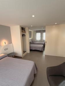 ein Hotelzimmer mit zwei Betten und einer Couch in der Unterkunft Hostal Tarrés in Anglés