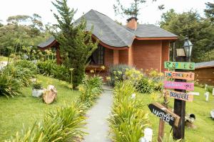 ein kleines Haus mit einem Schild davor in der Unterkunft Pousada Chales da Mantiqueira - Campos do Jordão in Campos do Jordão