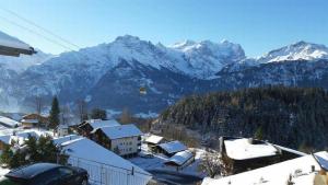 a village with snow covered mountains in the background at Chalet Hofer in Hasliberg Wasserwendi