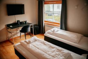 a hotel room with two beds and a desk and a window at Lødingen Brygge in Lødingen