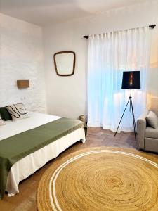 ein Schlafzimmer mit einem Bett, einem Stuhl und einem Teppich in der Unterkunft Mas Ribas Hotel i Esdeveniments in Palamós