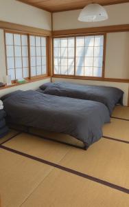 2 Betten in einem Zimmer mit Fenstern in der Unterkunft 森の中で仲間や家族とゆっくり過ごせる温泉付コテージ 会員制別荘地で広大なプライベート空間 ペット可 那須高原りんどうハウス in Nasu