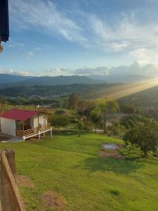 Blick auf ein grünes Feld mit einem Haus in der Unterkunft Cabañas Villa Luz in San Agustín + 1 Foto