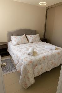 Un dormitorio con una cama grande con un edredón blanco. en Moderno Depto 3D 2B con Estacionamiento en Concepcion, en Concepción
