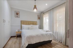une chambre blanche avec un lit et une fenêtre dans l'établissement Modern Family Haven with Garden Sleeps 8, à Sandton 56 autres photos