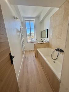 马赛La Bastide des Trembles的带浴缸、水槽和窗户的浴室