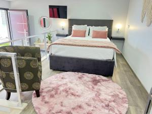 a bedroom with a large bed and a pink rug at Studio Refúgio in Ponta do Sol