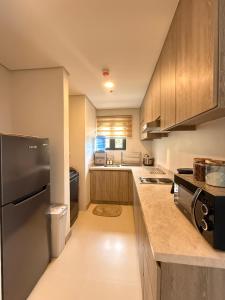 Una cocina con gabinetes de madera y un refrigerador negro. en The Banyan Rest, en Balibaguhan