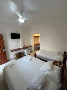 um quarto de hotel com duas camas e uma TV de tela plana em Pousada Acqua Azul em Bertioga